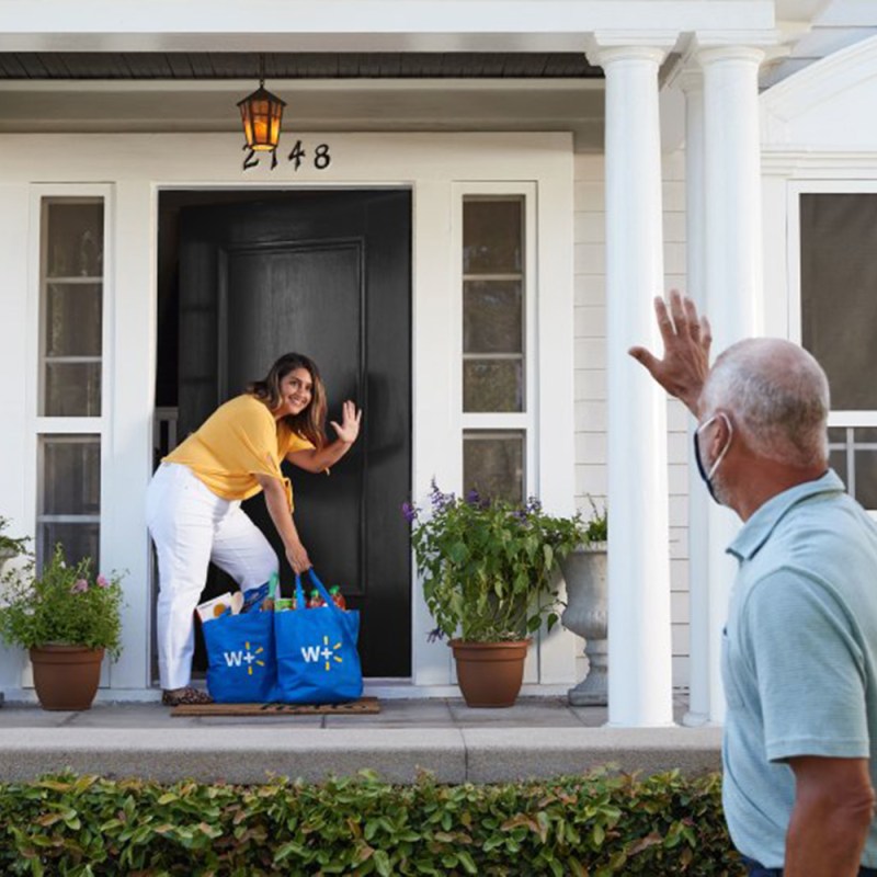 A woman waving to a man outside a house.