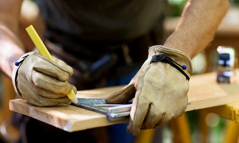 best work gloves carpenter measuring a wooden plank