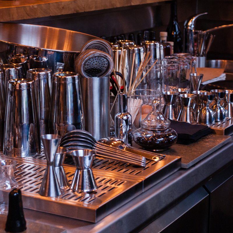 Stack of bar tools on a stainless steel counter.