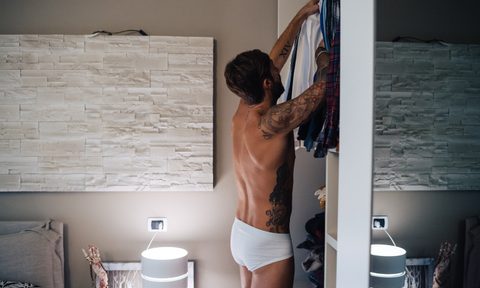 Man in underwear getting dressed in a bedroom