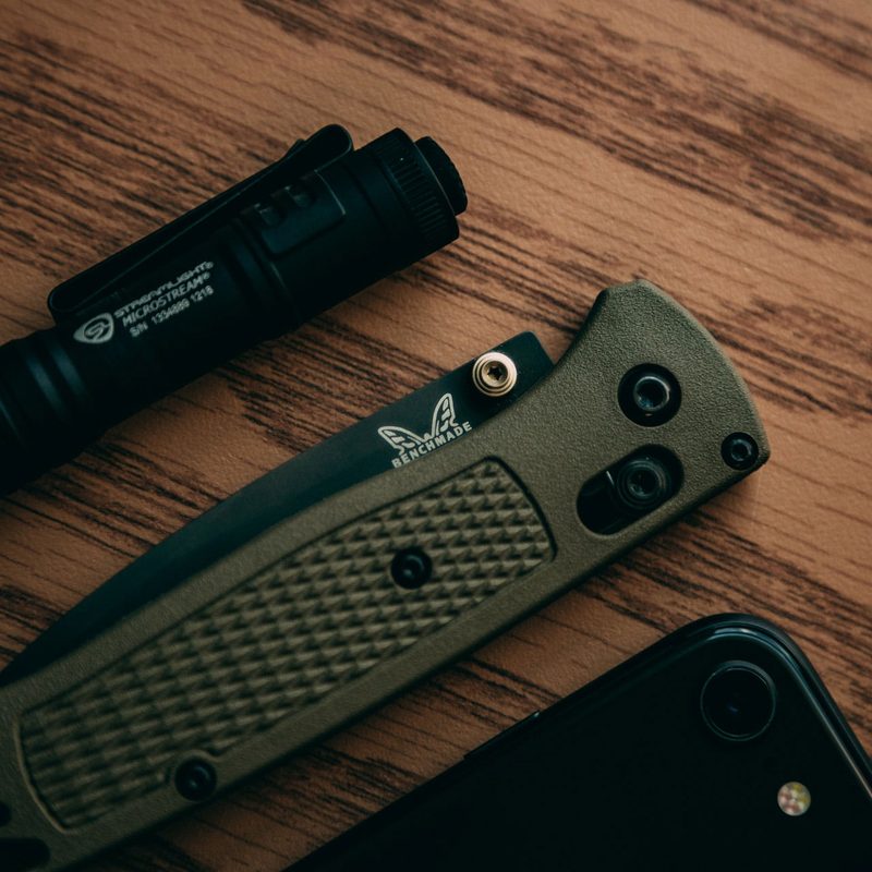 Overhead view of everyday carry items, including a penlight, pocket knife, and smartphone