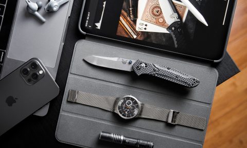 Flat-lay of a tablet with a watch, penlight, and pocketknife lying next to it