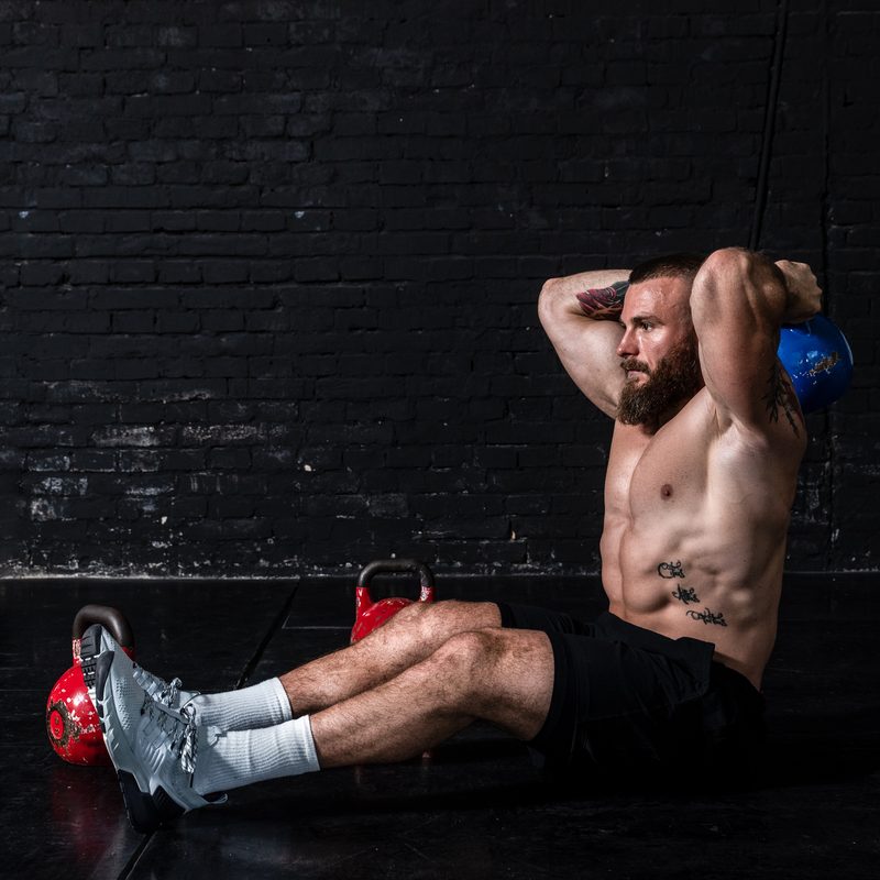 Man sitting on the ground working out.