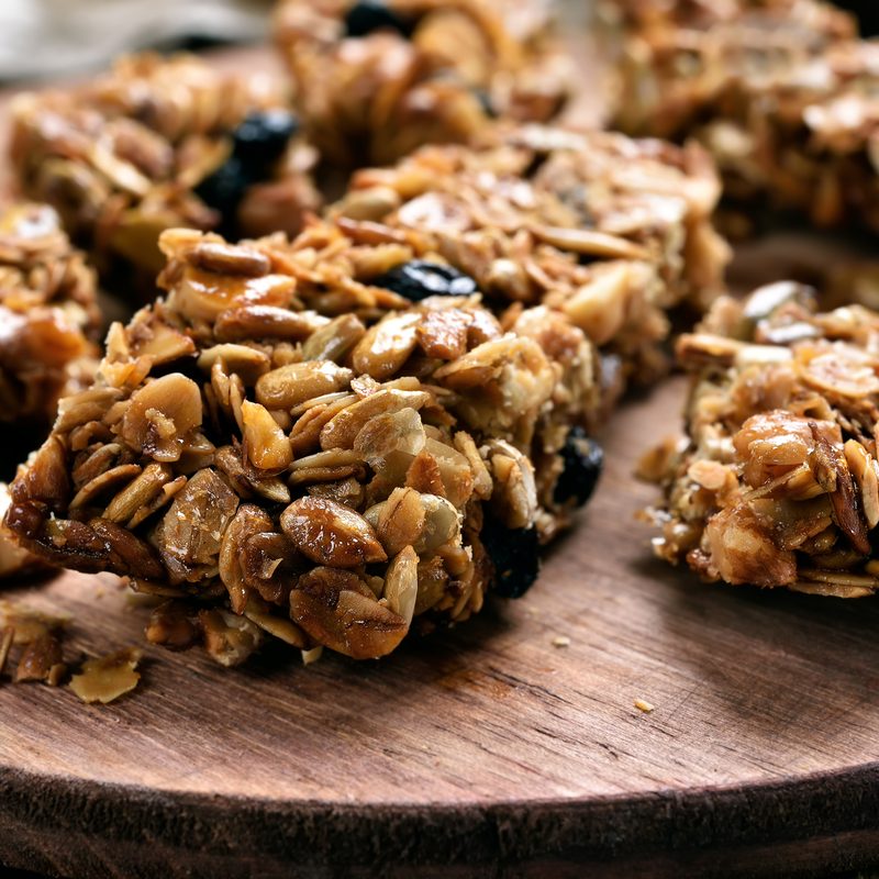Granola pieces on wooden board, close up view