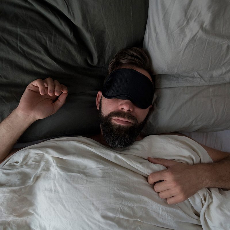 Man in bed with sleep mask.
