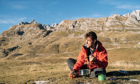 best mres backpacker prepares meal on camp stove in mountains