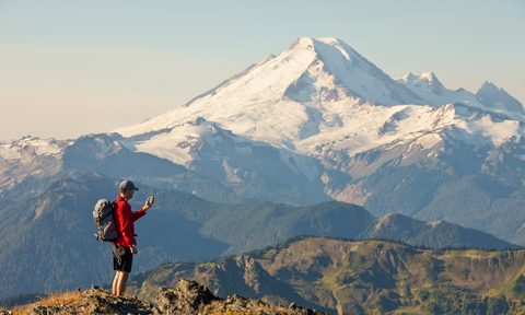 us national park service app a backpacker checks his phone while hiking in north cascades