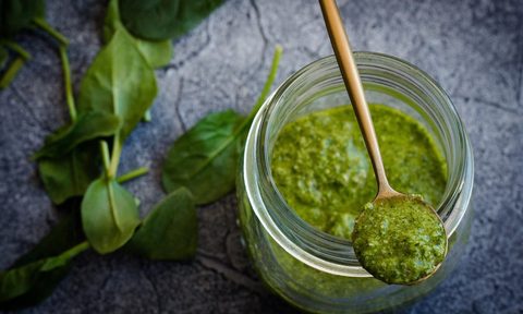 A jar and a spoonful of basil pesto