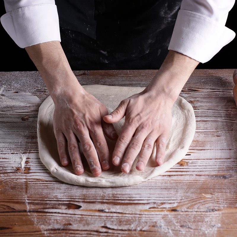 A person preparing pizza dough