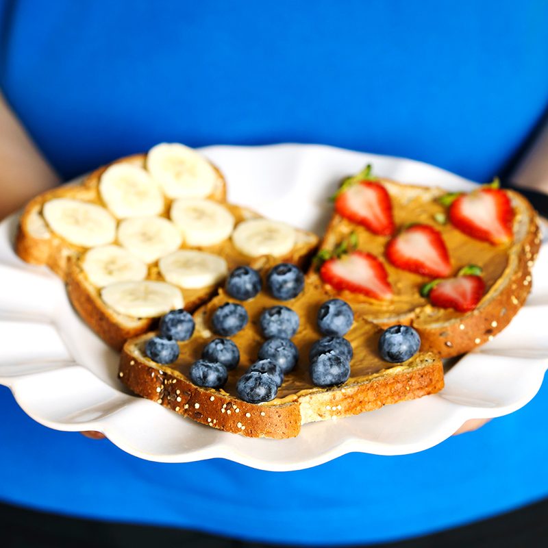 Assorted toasts with banana slices, blueberries, and strawberries.
