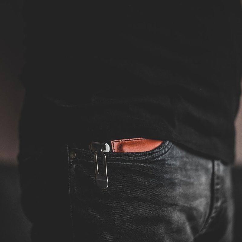 Close-up of a pocket knife and wallet peeking out of the pocket of someone's jeans