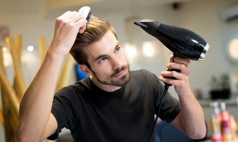 Man drying his hair using a hair dryer