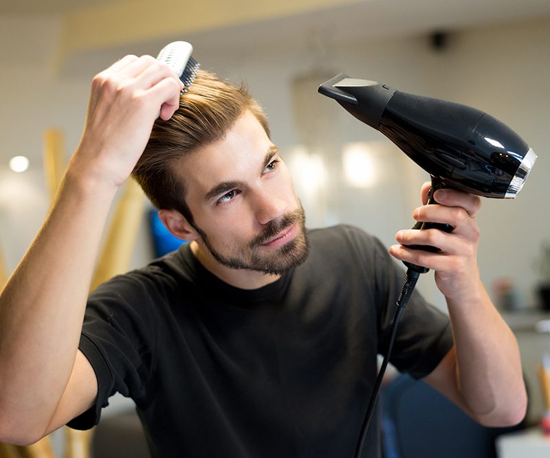 A person drying their hair using a hair dryer.