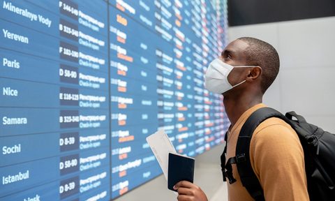 cdc vaccinated americans travel traveler wearing a facemask at the airport and looking flight schedule
