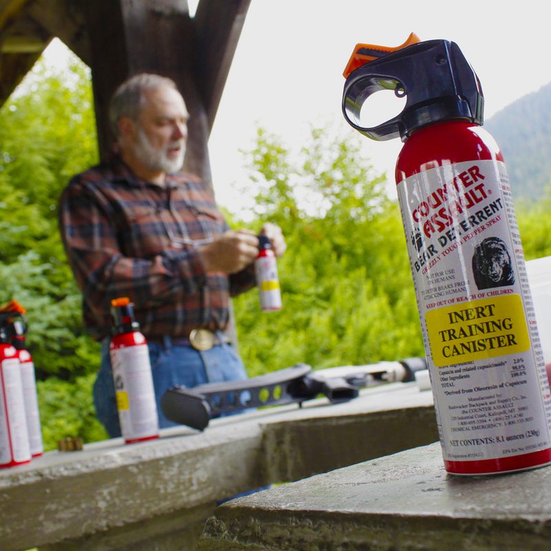 Man testing a can of Counter Assault Bear Deterrent in an outdoor setting.