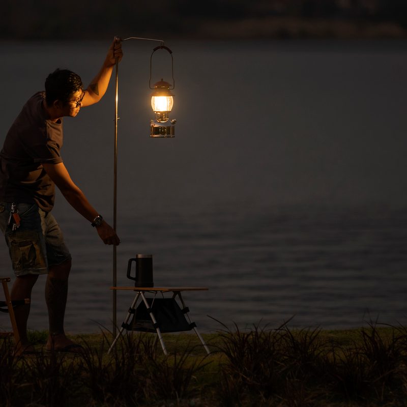 A man and an illuminated lantern near a lake.