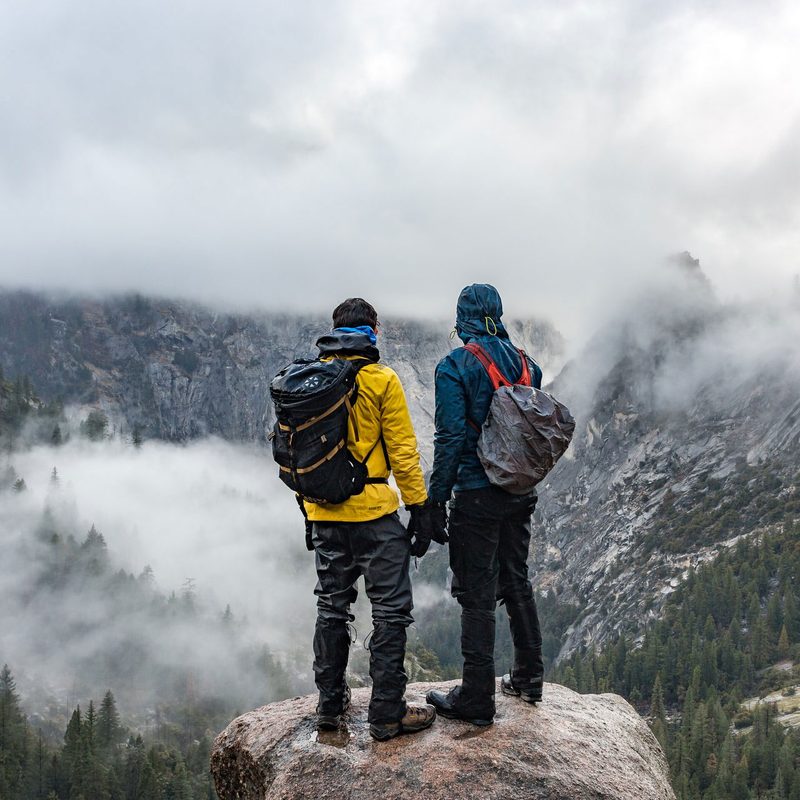 Two men standing near cliff during daytime in outdoor gear