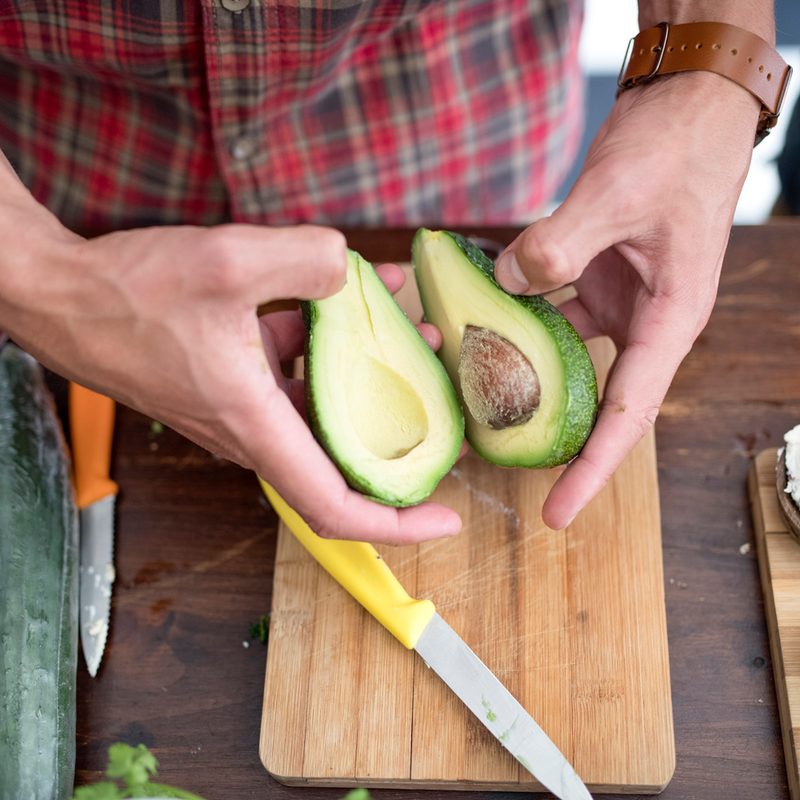 Man slicing up an avocado into two halves