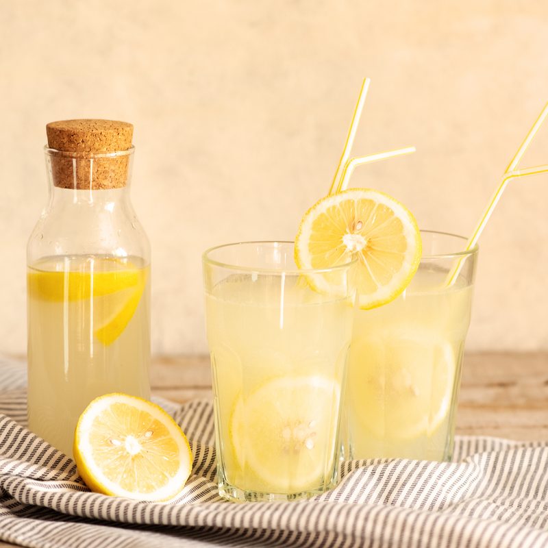 Jar of tasty fresh lemonade with lemons in background