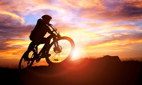 Mountain biker silhouette against the sunset concept for achievement, conquering adversity and exercising