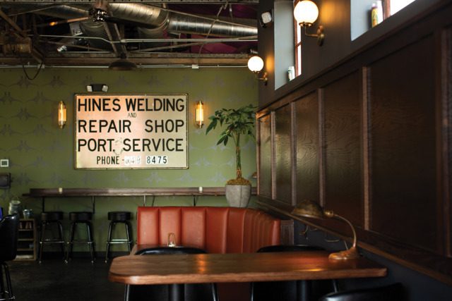The dining area of Never Never with a sign that says "Hines Welding and Repair Shop- Port. Service- Phone 6498475."