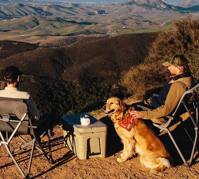two men with a yeti cooler and a dog