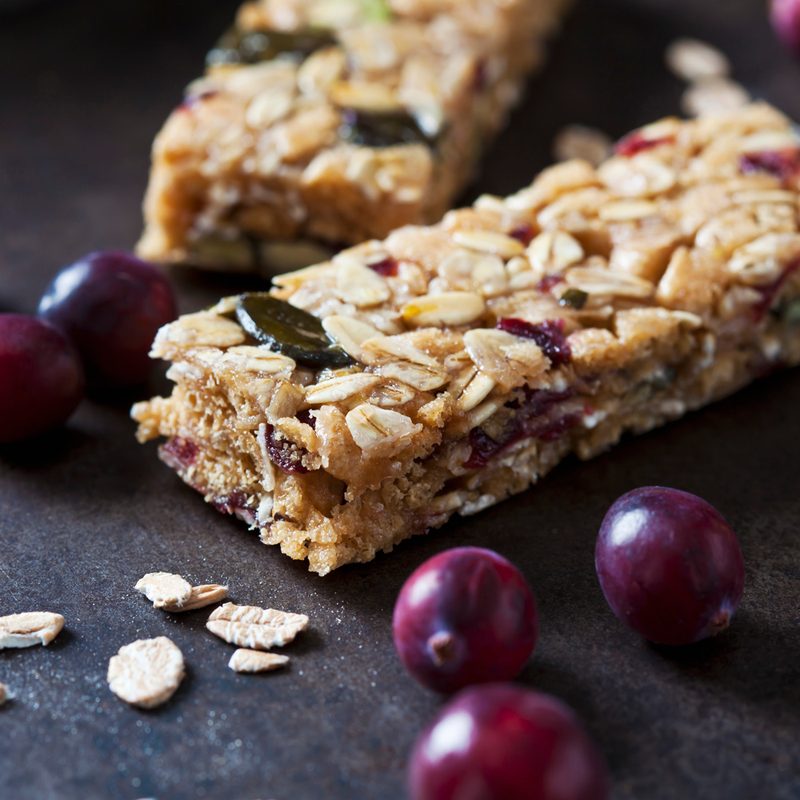 Closeup of a fruit granola bar on a dark surface.
