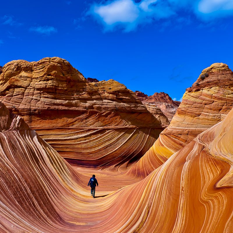 Hiker trekking the surreal rock formations at The Wave in Arizona