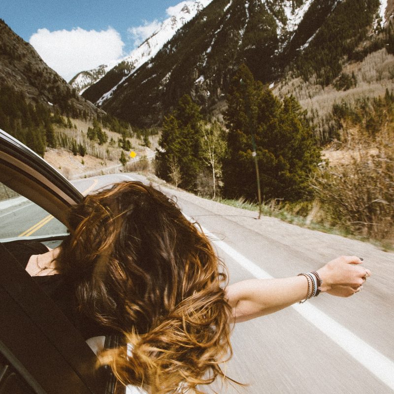 Woman leaning out of passenger window in a moving car.