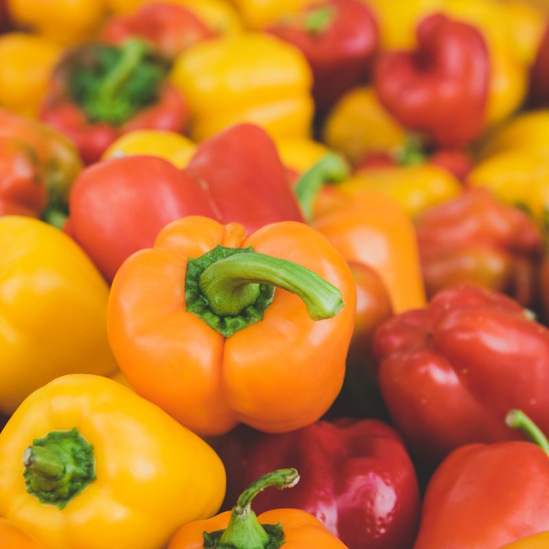 a pile of red, yellow, and orange bell peppers.