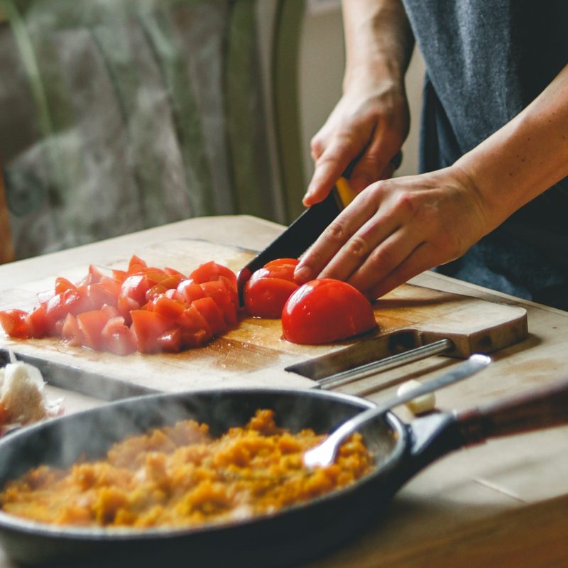 A person cutting up tomatoes for a healthy meal