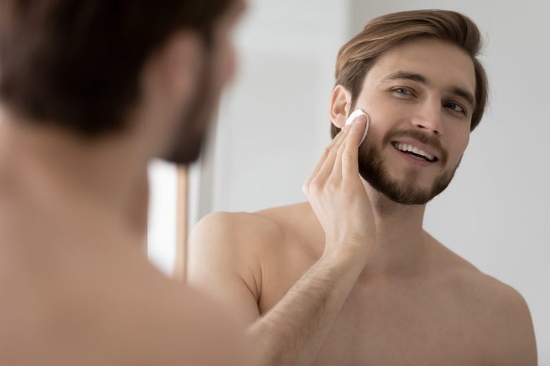 A man applying skincare products to his face.