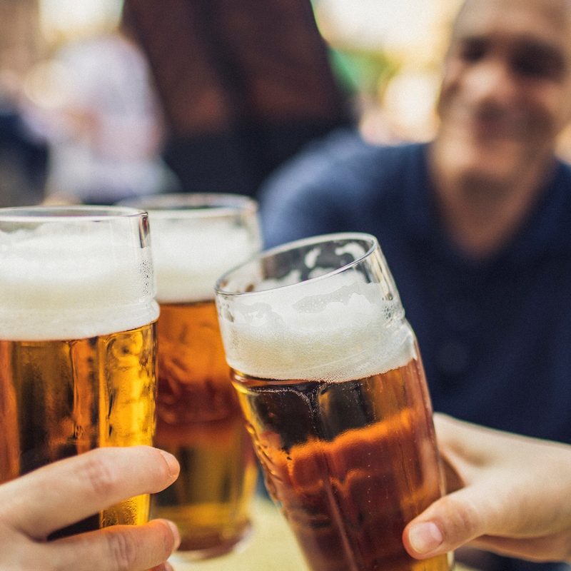 Three friends cheering with glasses of pilsner beer