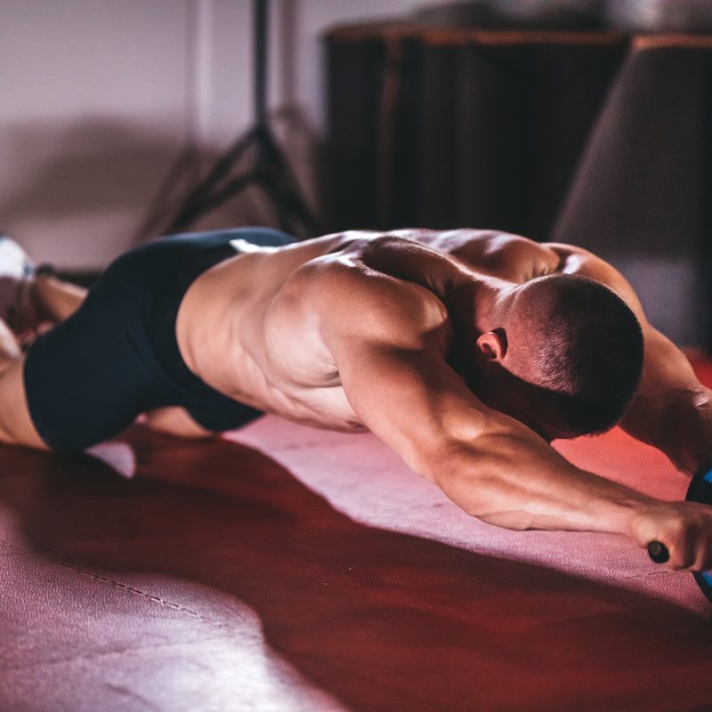 Man doing ab wheel in a home gym