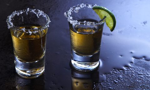 Two shot glasses rimmed with salt and a lime wedges
