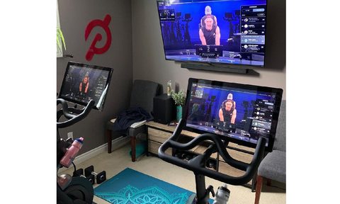 two Peloton bikes with classes streaming on the screens and a tv