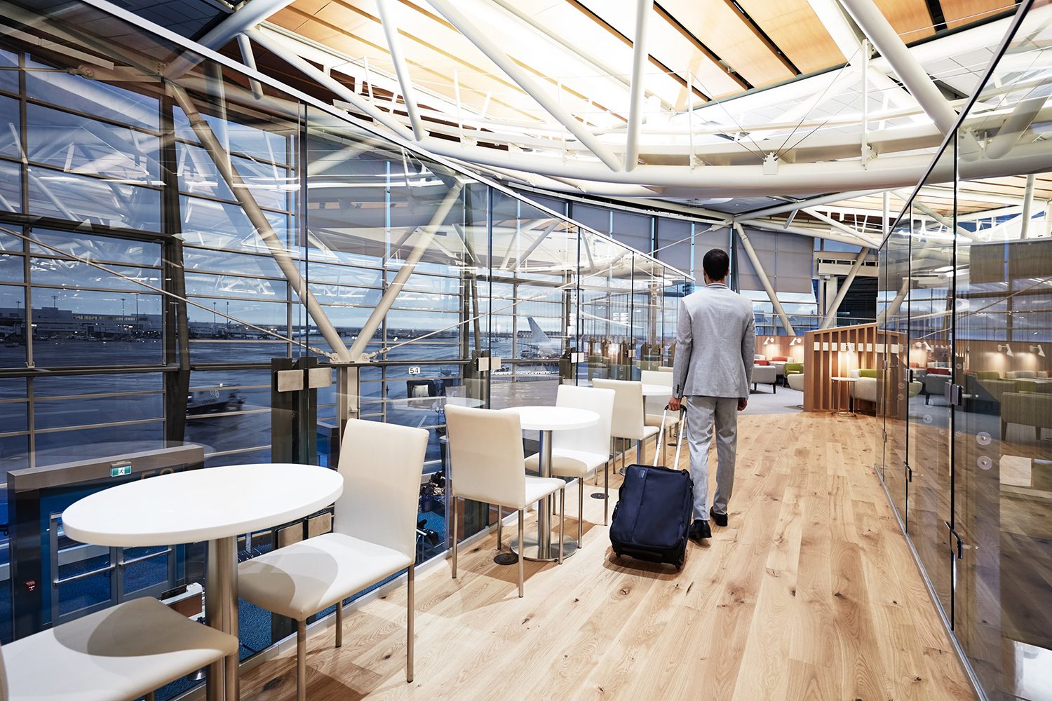 Man wheeling a rollaboard suitcase through a Priority Pass lounge in the Vancouver Airport