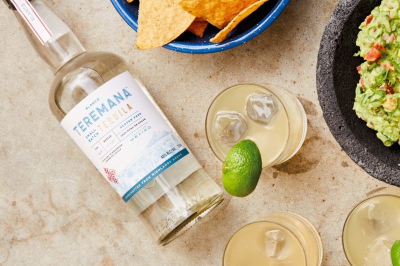 Shots and a bottle of Teremana and snacks on the sand.
