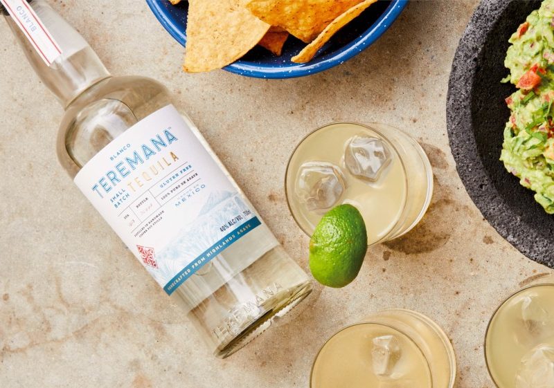 A Teremana Tequila bottle next to a lime-rimmed drink and guacamole.