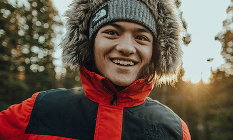 Smiling person in a North Face beanie and winter coat outdoors.