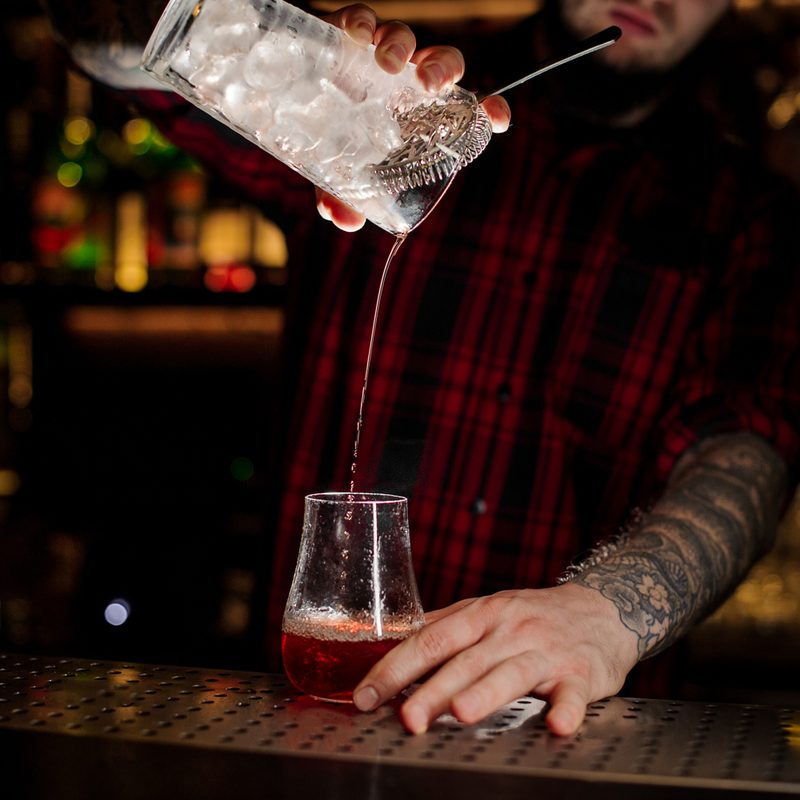 A bartender pouring a Sazerac cocktail.