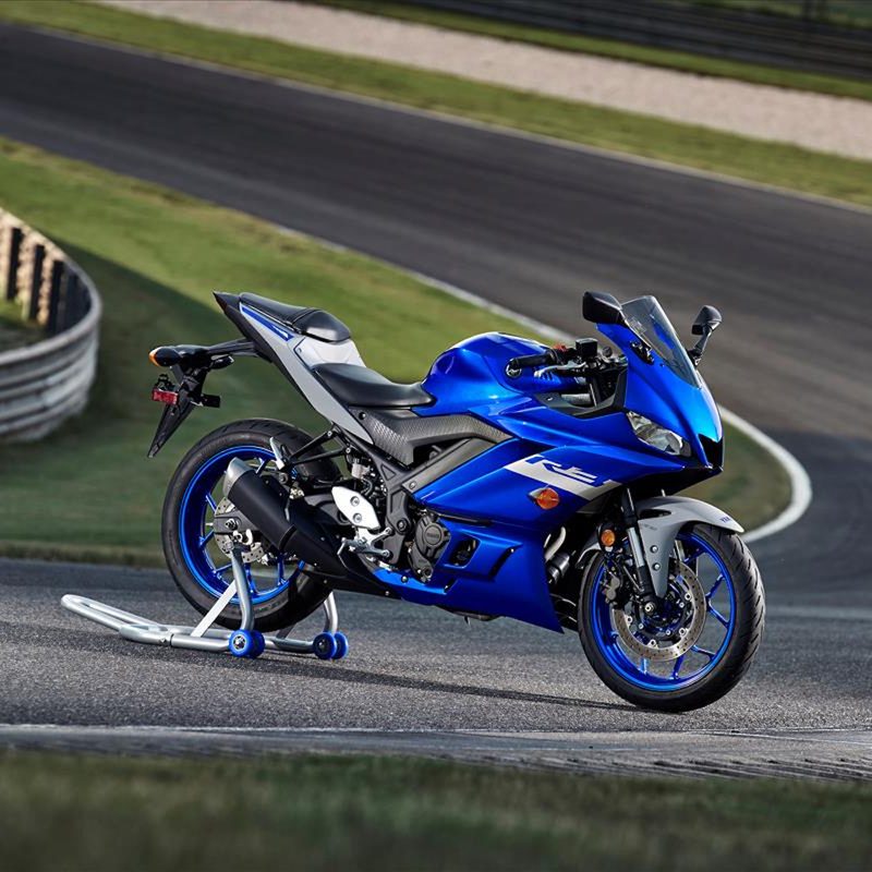 Blue Yamaha YZF-R3 motorcycle sitting at a corner on a racetrack with a stand