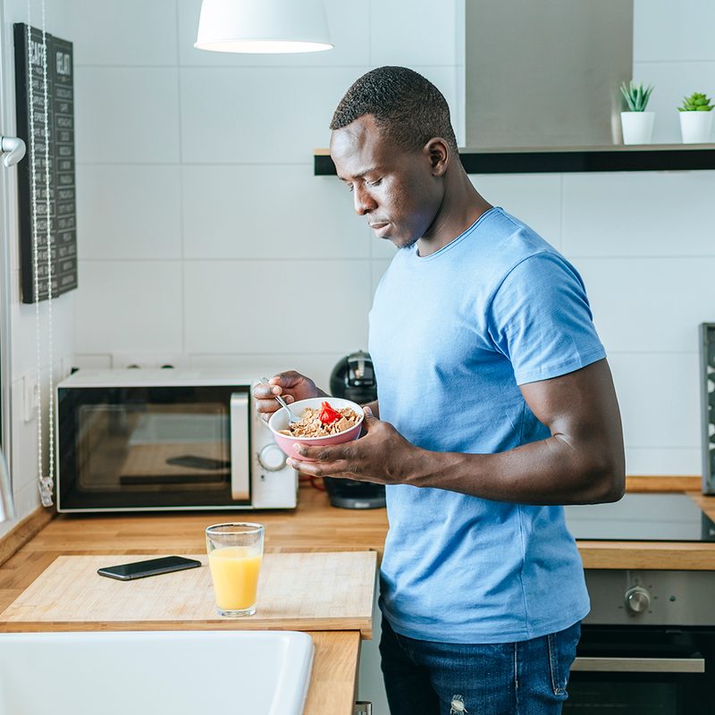 Young man having breakfast in kitchen at home