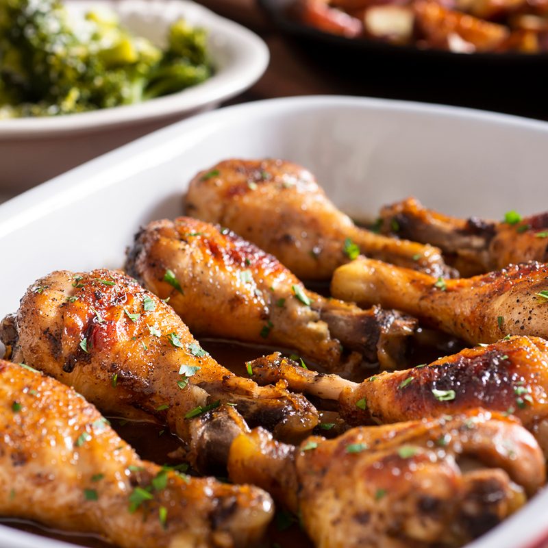 Marinated chicken legs in a baking dish with steamed broccoli and roasted potatoes
