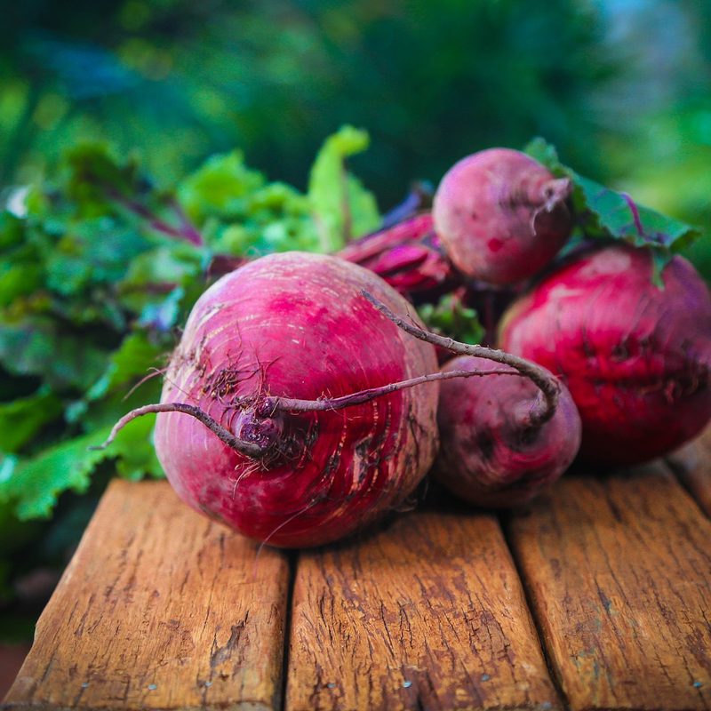 raw beets sitting on a wooden table.