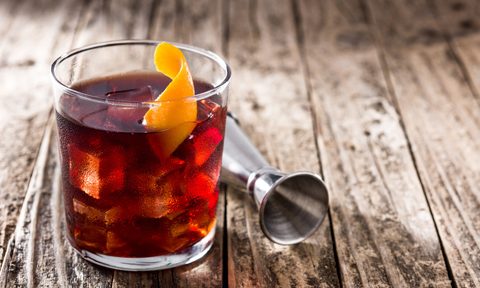 Boulevardier cocktail and orange zest on wooden table