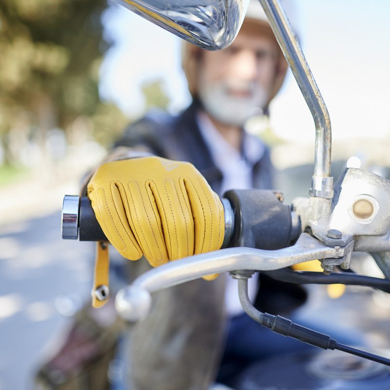 Close-up of hand with yellow gloves on motorcycle handlebar