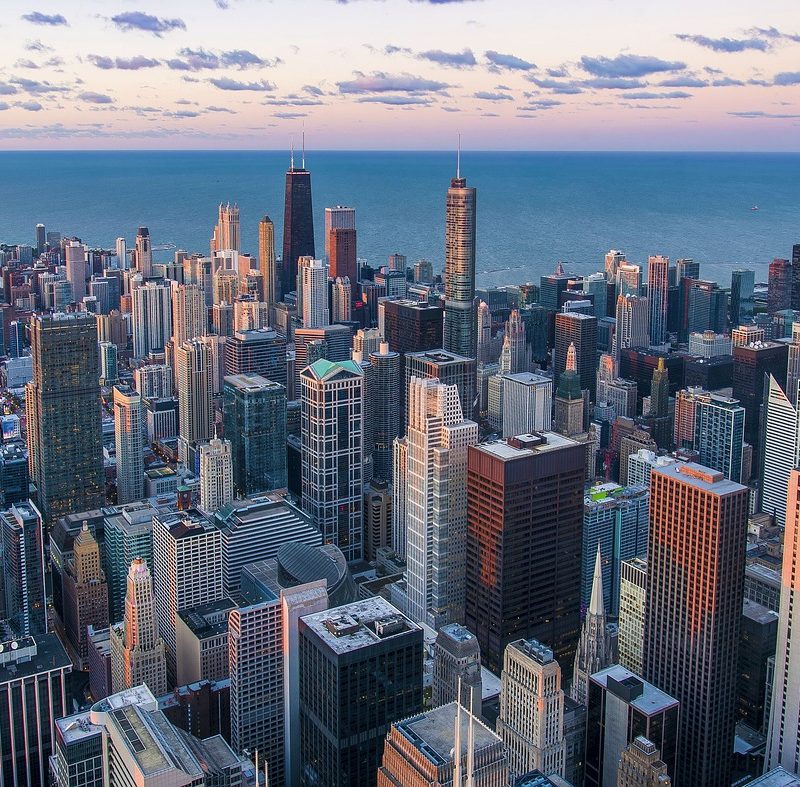 An aerial shot of downtwon Chicago with Lake Michigan visible in the distance. 