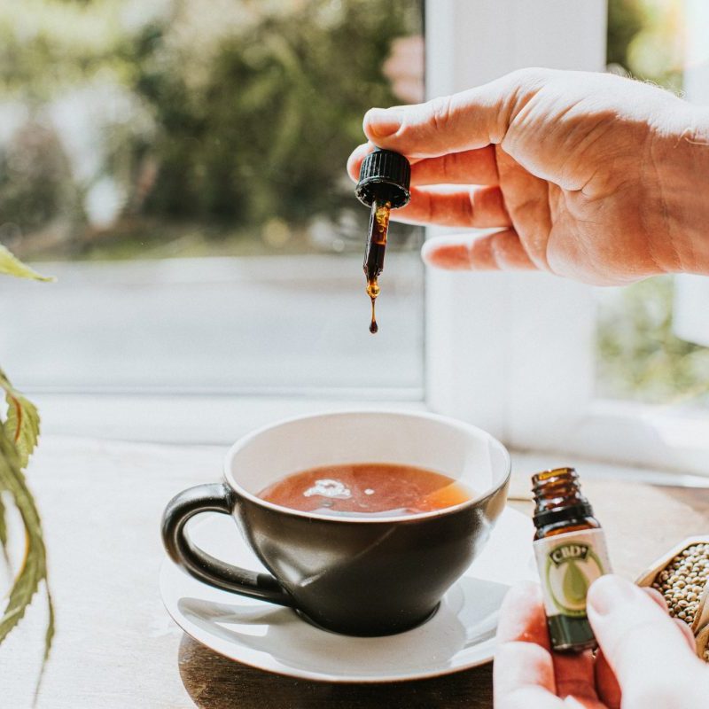 Adding CBD oil to a cup of tea.