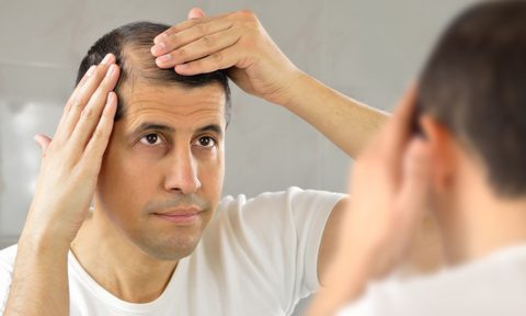 A man lookin at his thinning hair